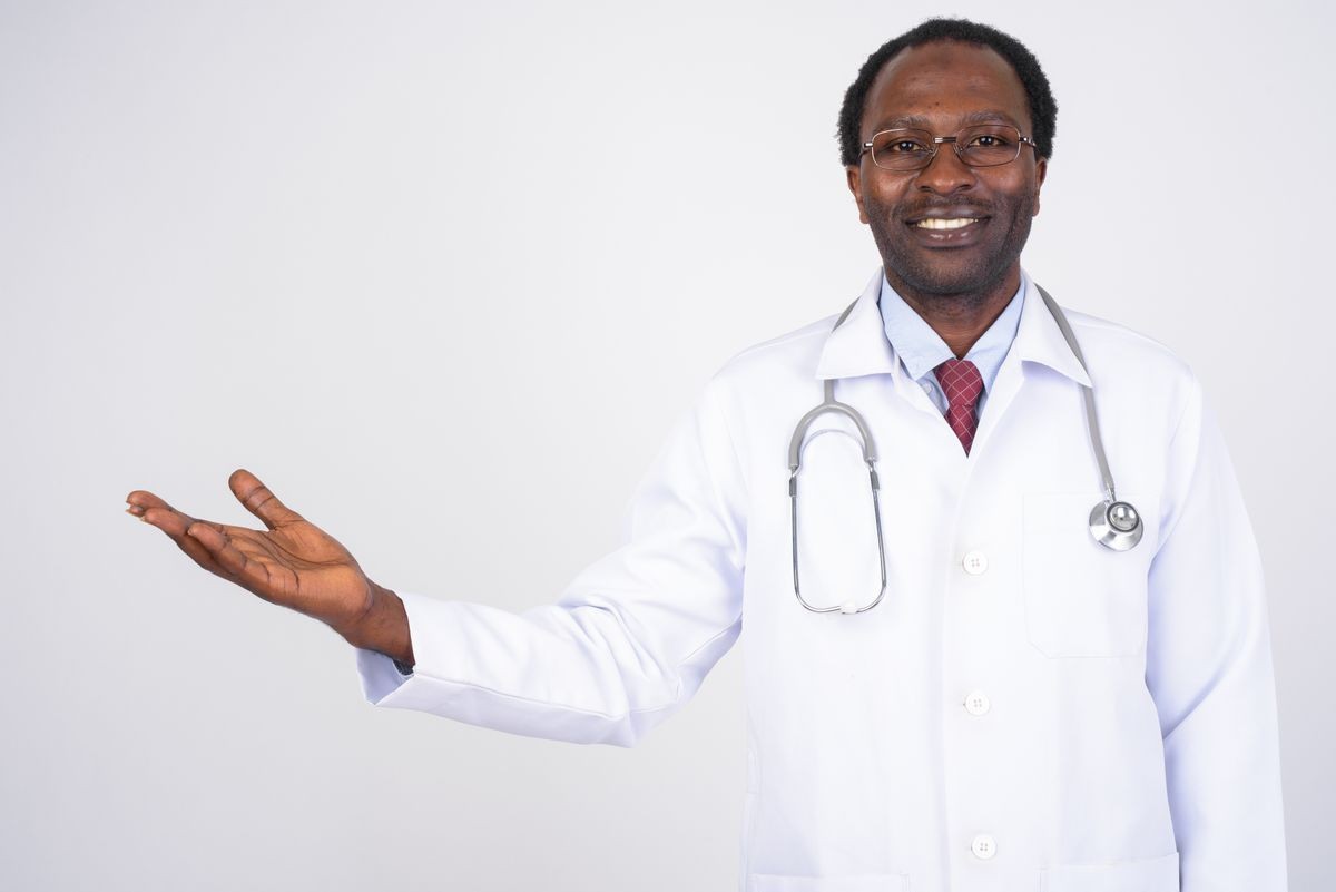 Portrait of happy African man doctor showing something